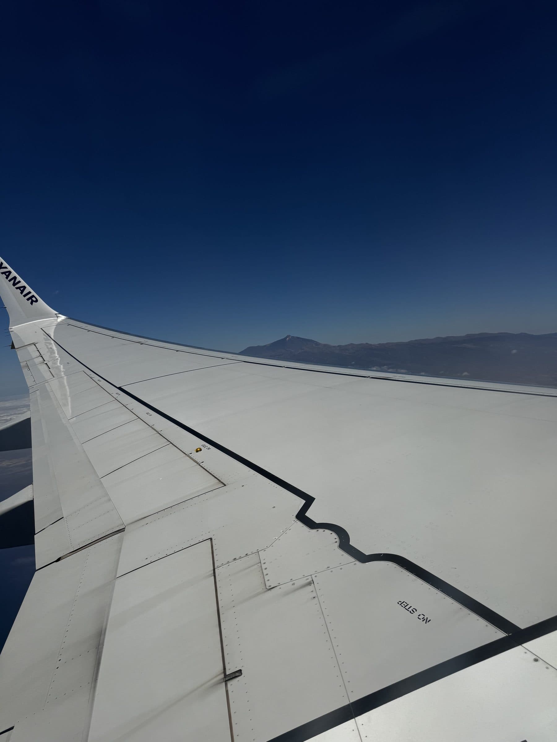 Looking out over the Ryanair wing, winglet branding visible, with Mount Teide and the Tenerife coastline in the distance.
